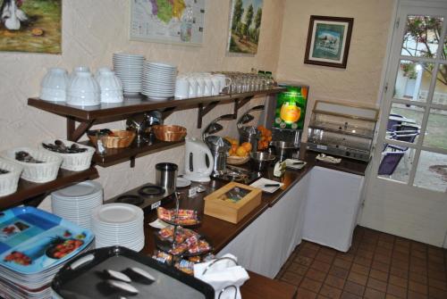 a kitchen with a counter with plates and dishes at Logis Hôtel & Restaurant Le Fleurance in Fleurance
