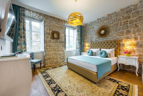 a bedroom with a bed and a stone wall at Dominus Rooms in Dubrovnik