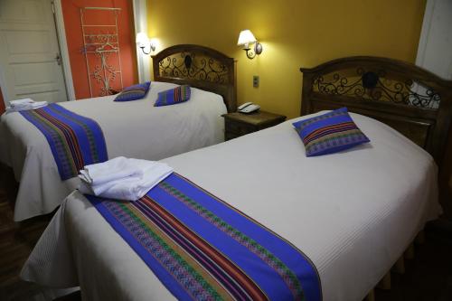 two beds in a hotel room with white sheets at Isabela Hotel Suite in La Paz