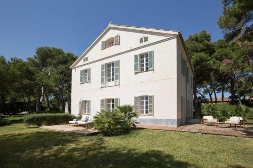 a large white house with chairs and trees at Can Simoneta - Adults Only in Canyamel