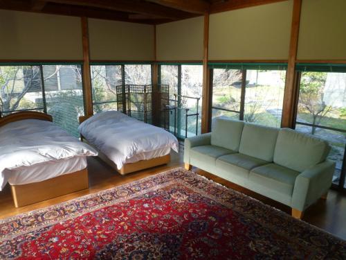 a living room with a couch and a bed and windows at Wakihonjin in Kikugawa