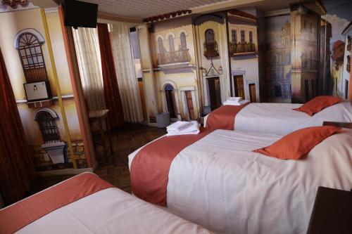 a room with four beds in it with paintings on the walls at Isabela Hotel Suite in La Paz