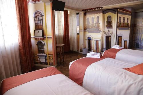a room with three beds with red and white sheets at Isabela Hotel Suite in La Paz