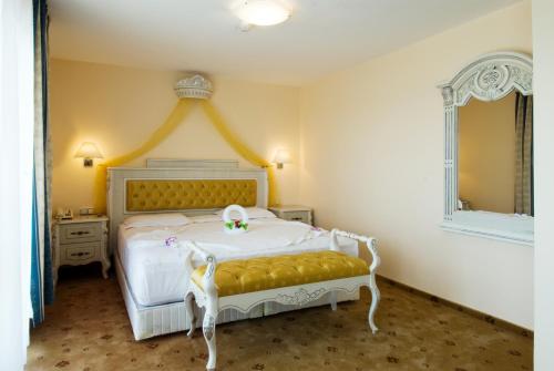 a bedroom with a white bed with a yellow headboard at Duni Pelican Hotel - All Inclusive in Sozopol