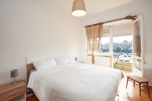 een witte slaapkamer met een wit bed en een raam bij Sea La Vie (3 minutes walk to the beach) in Carcavelos