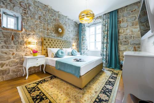 a bedroom with a bed and a stone wall at Dominus Rooms in Dubrovnik