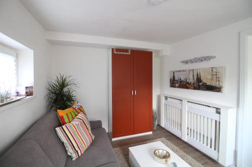 a living room with a couch and a red door at Elbperle94 in Hamburg