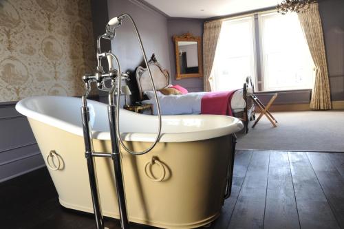 a bath tub with a shower in a bathroom at The Tunbridge Wells Hotel in Royal Tunbridge Wells
