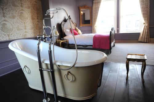 a bath tub in a room with a bed at The Tunbridge Wells Hotel in Royal Tunbridge Wells