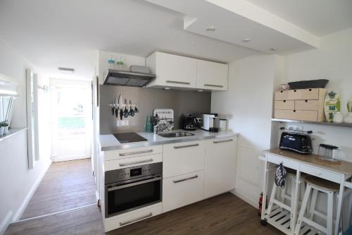 a kitchen with white cabinets and a stove top oven at Elbperle94 in Hamburg