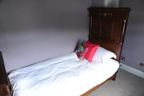 a bed with a red pillow on top of it at The Tunbridge Wells Hotel in Royal Tunbridge Wells