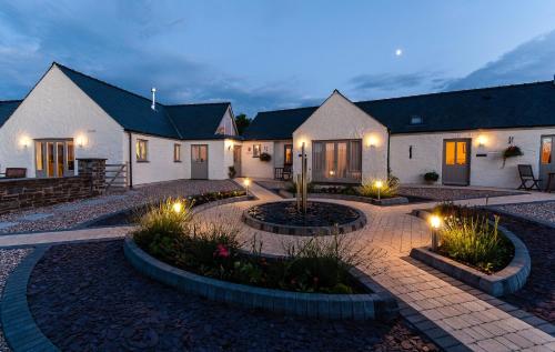 a house with lights in a courtyard at night at Canaston Oaks in Narberth