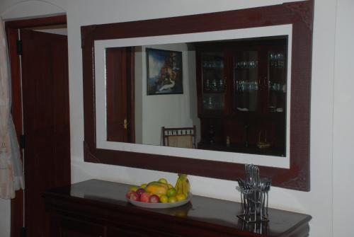 a mirror on a wall with a bowl of fruit on a table at Colonial 4 B/R Home, Great for Families, Coonoor in Coonoor