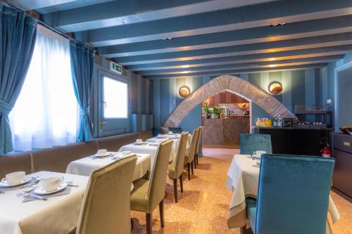 a dining room with white tables and chairs and an arch at Hotel Tiziano in Venice