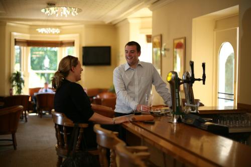 a man and a woman standing at a bar at B/W Plus Buxton Lee Wood Hotel in Buxton