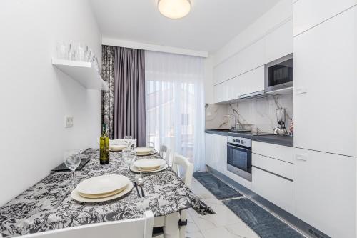 a white kitchen with a dining table with white cabinets at Villa Palma Krk in Krk