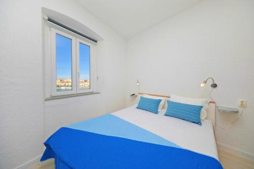 a bedroom with a blue and white bed with a window at Sea View Studio Apartment in Zadar