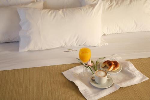 萨尔塔艾尔代萨尔塔酒店的一张床，含早餐、一杯咖啡和一杯橙汁