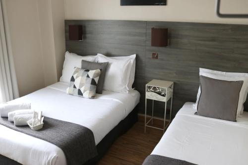 2 bedden in een hotelkamer met wit en grijs bij Hotel Le Transat Bleu in Duinkerke