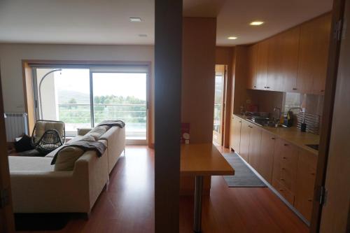 Una sala de estar con un sofá blanco y una cocina. en Terraços de Seixas, en Caminha