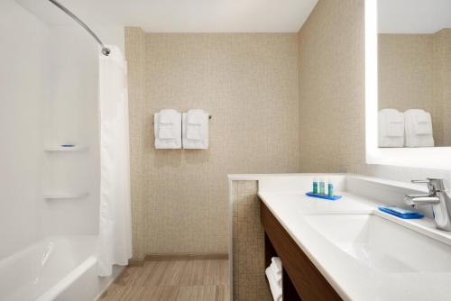 a bathroom with a sink and a tub and a mirror at Holiday Inn Express & Suites - Cincinnati South - Wilder by IHG in Wilder