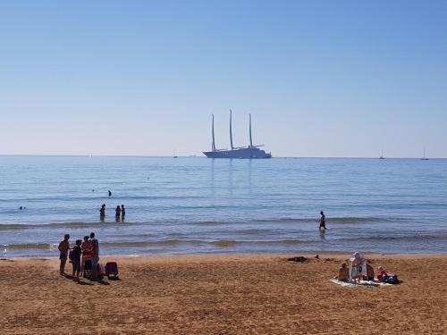 a group of people on a beach with a boat in the water at B&B Bianco E Blu in Marina di Ragusa