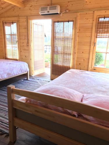 a bedroom with two beds in a log cabin at Jaunbirzes in Vecsaule