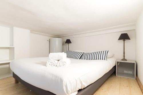 Un dormitorio blanco con una gran cama blanca con dos toallas. en L'Escale, en Montpellier