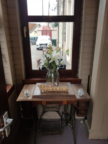 a vase of flowers on a table in front of a window at The Old Cross Inn in Blairgowrie