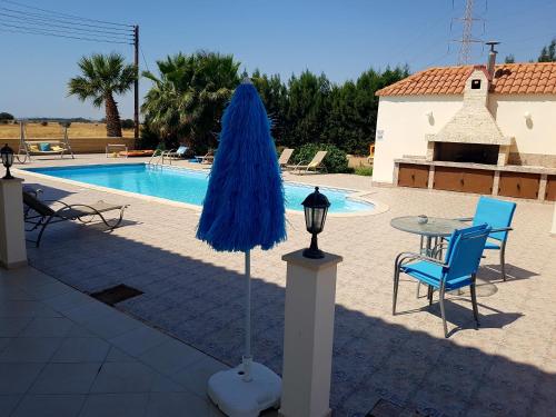 a patio with a table and chairs and a blue umbrella at Larnaca Mansion Ideal for 3 Families or more in Larnaka