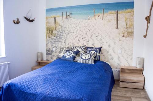 1 dormitorio con 1 cama azul y un mural de playa en Pocztówka en Ustka