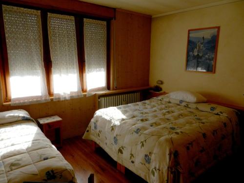 a bedroom with two beds and two windows at Albergo Adele in Bormio