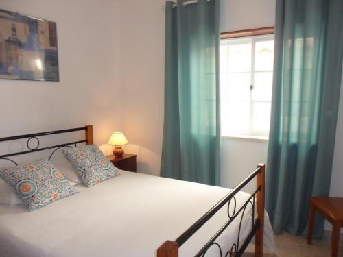 a bedroom with a bed with blue curtains and a window at Consolação Surf & Beach Apartment in Consolação