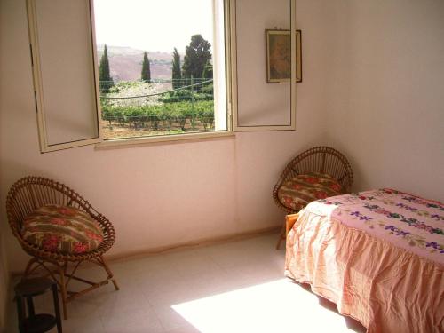 a bedroom with a bed and two chairs and a window at Villetta San Giovanni in Calatafimi