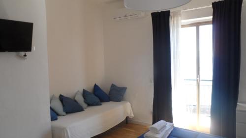 Habitación con sofá, almohadas azules y ventana. en Bluoltremare en Realmonte