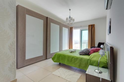 a bedroom with a green bed and a large window at Seafront Apartment Sliema in Sliema