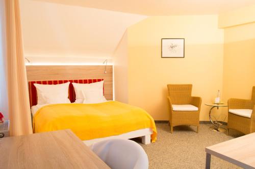 a hotel room with a yellow bed and a chair at Hotel Gewürzmühle in Berching