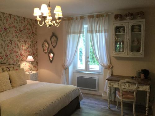 a bedroom with a bed and a window and a desk at L'Orangerie de Camperos in Barsac