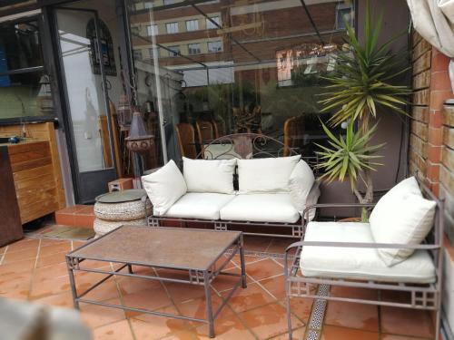 a patio with two white couches and a coffee table at Casa con vistas in Barcelona
