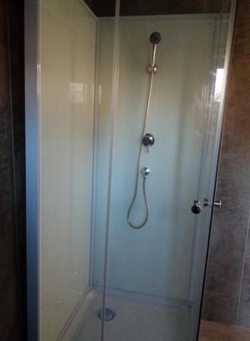 une douche avec une porte vitrée dans une salle de bain dans l'établissement Petit Chalet Chez Marcelline, à Amécourt