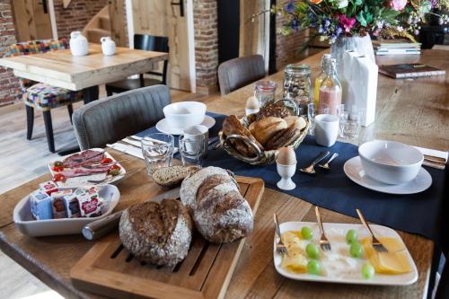 a wooden table with bread and pastries on it at Bed & Breakfast De Schoppe in Winterswijk