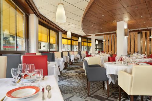 ein Restaurant mit weißen Tischen und roten Stühlen in der Unterkunft Hôtel Roissy in Lourdes