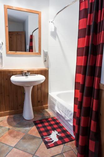 a bathroom with a sink and a tub and a mirror at Gîte du Mont-Albert - Sepaq in Sainte-Anne-des-Monts