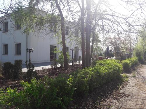 a white house with trees and bushes in front of a road at Centrum Konferencyjne Brancon in Babimost