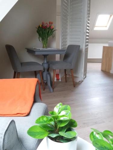 a dining room table with two chairs and a table with flowers at Mille Étoiles in Moorsel
