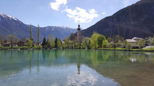 a lake with a church in the middle of a town at Chalet am See in Nassereith
