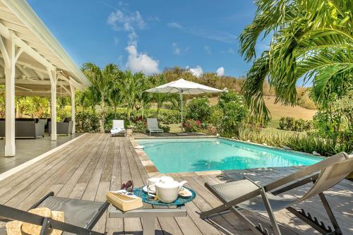 a swimming pool with chairs and a table next to a deck at Villas Palm in Le Vauclin