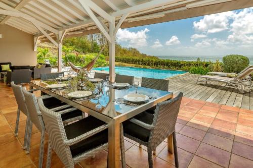 a dining room with a table and chairs and a pool at Villas Palm in Le Vauclin