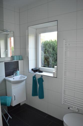 een witte badkamer met een wastafel en een raam bij Ferienwohnung Gravemeier in Ladbergen
