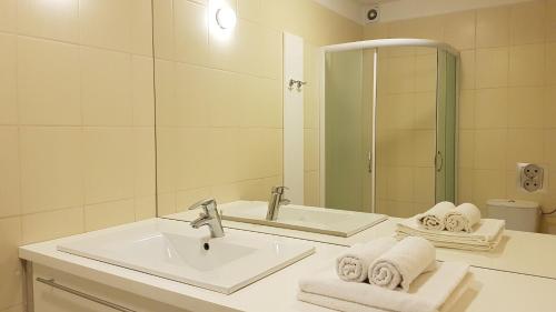 a bathroom with a sink and a mirror and towels at Apartament z ogrodem Wiśniowy Sad in Kołobrzeg